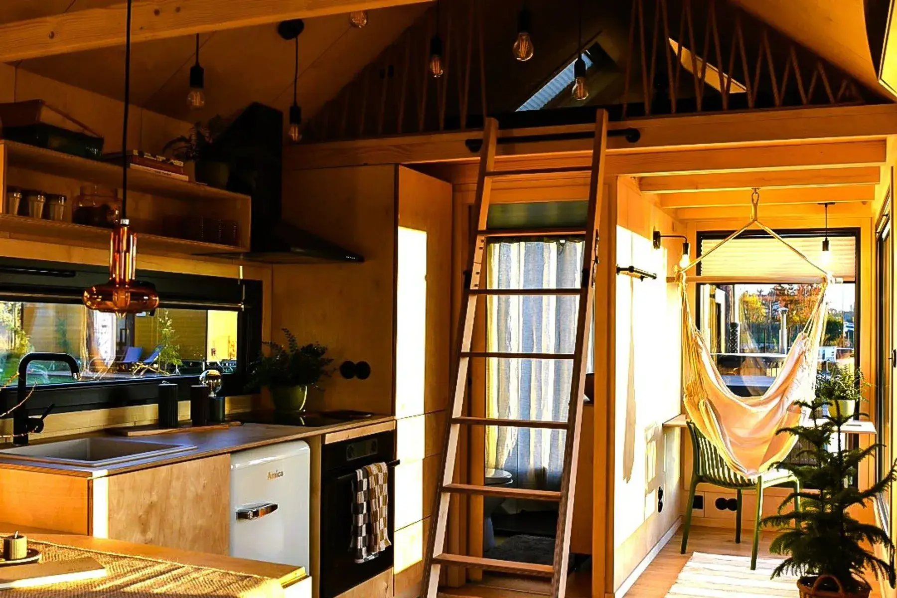 Dentro de una tiny house: la cocina, una escalera al altillo y una hamaca junto a la ventana