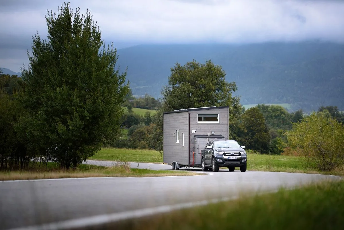 Une tiny house sur remorque livrée le long d’une route de campagne